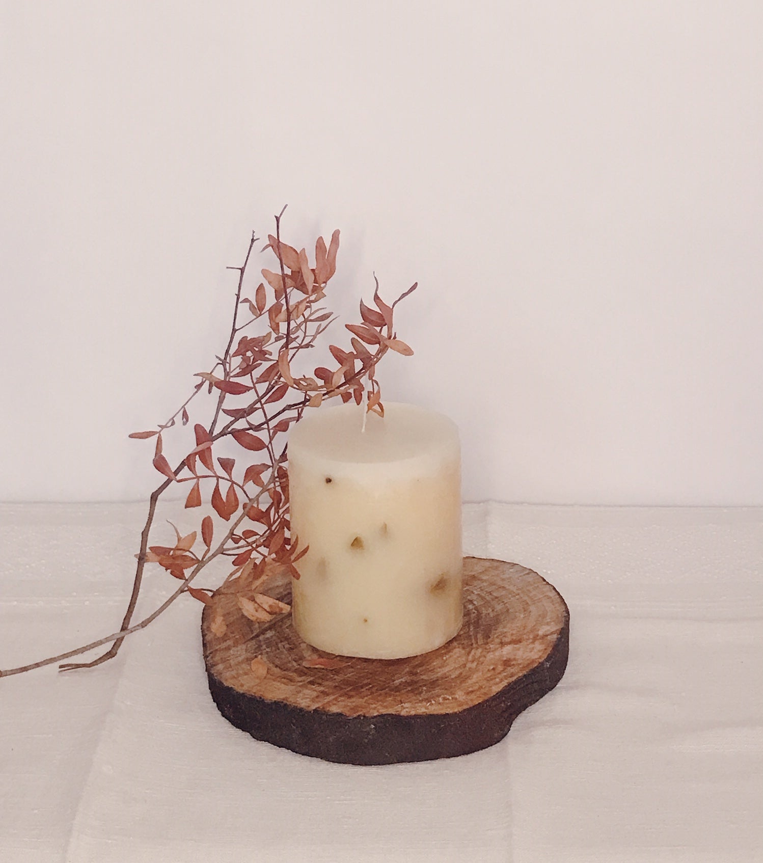 Hero Aromatic Candle displayed on a rustic wood slice with dried leaves, evoking romance and tranquility.
